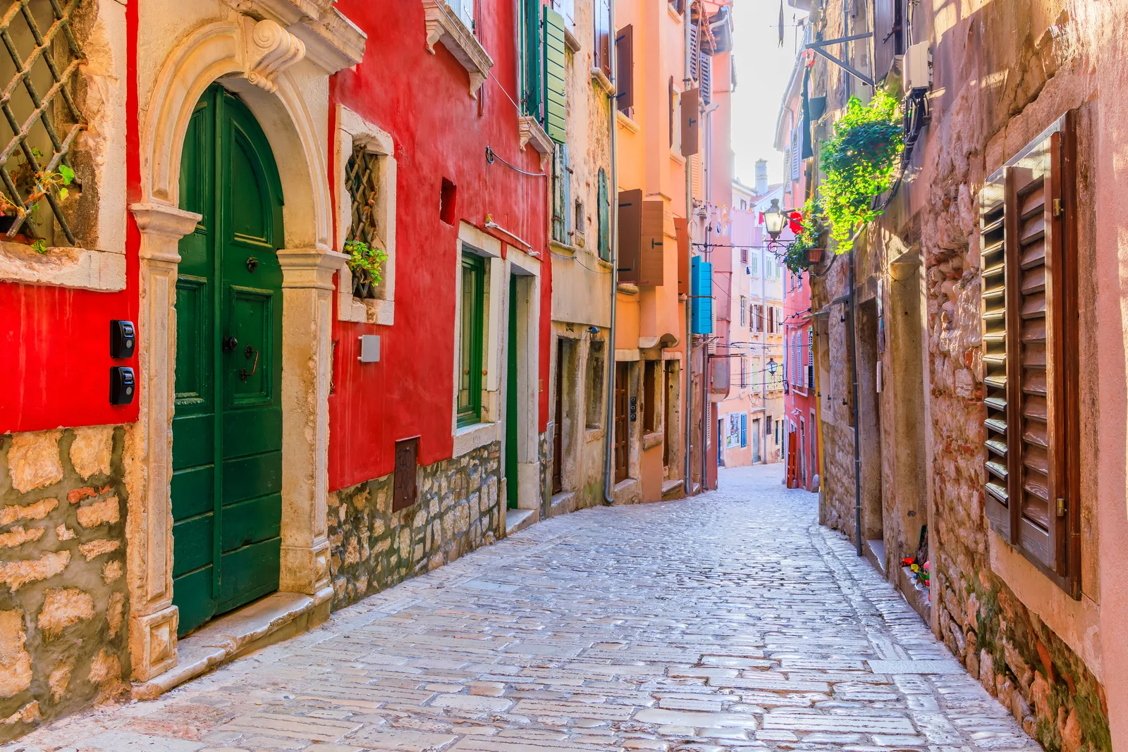 A colourful cobbled lane in Rovinj old town with a green door and red facade