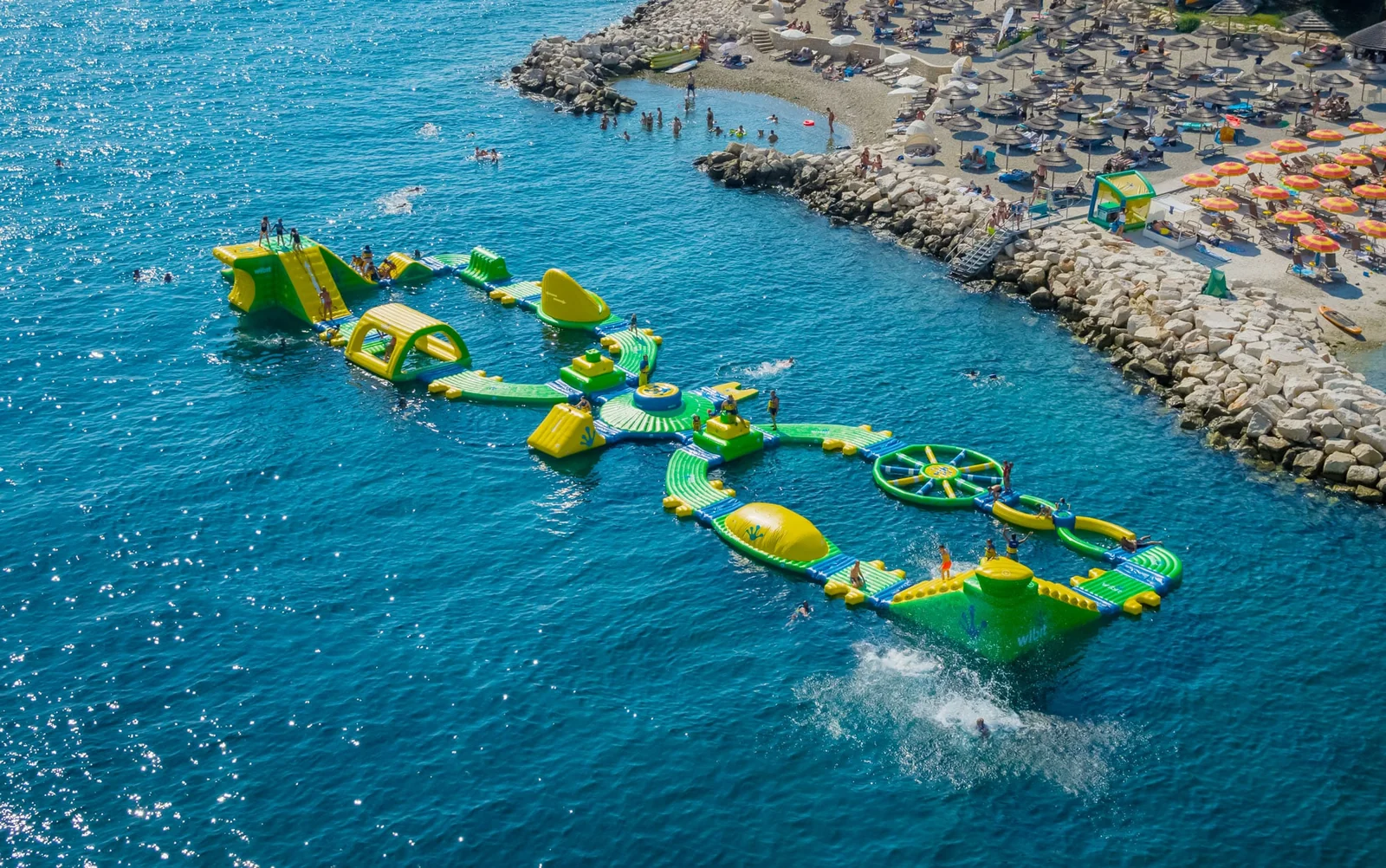 A Wibit floating inflatable water park off a beach