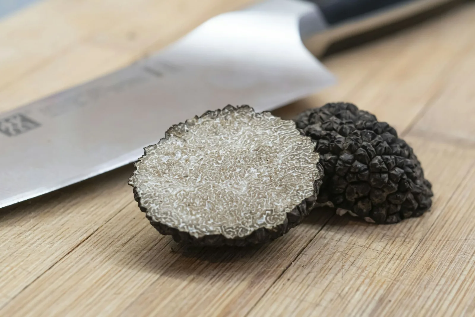 A black Istrian truffle whole and sliced open showing marbled flesh