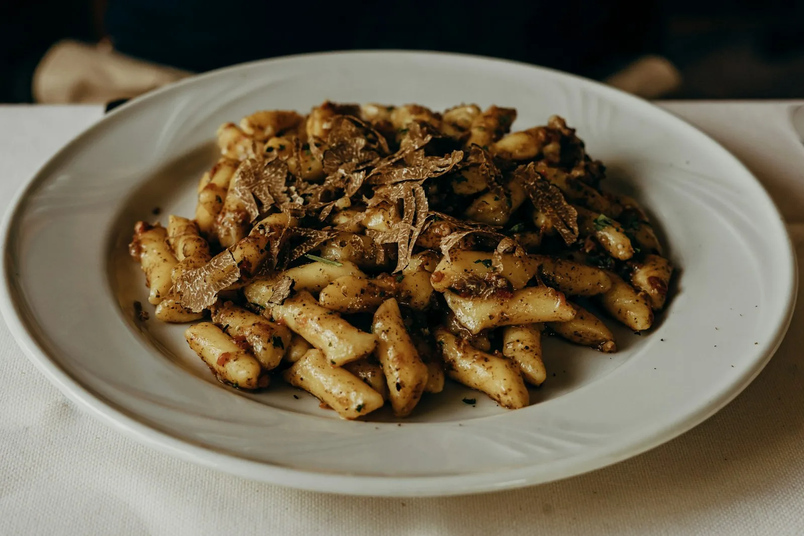 Fuži pasta topped with shaved white truffle on a plate