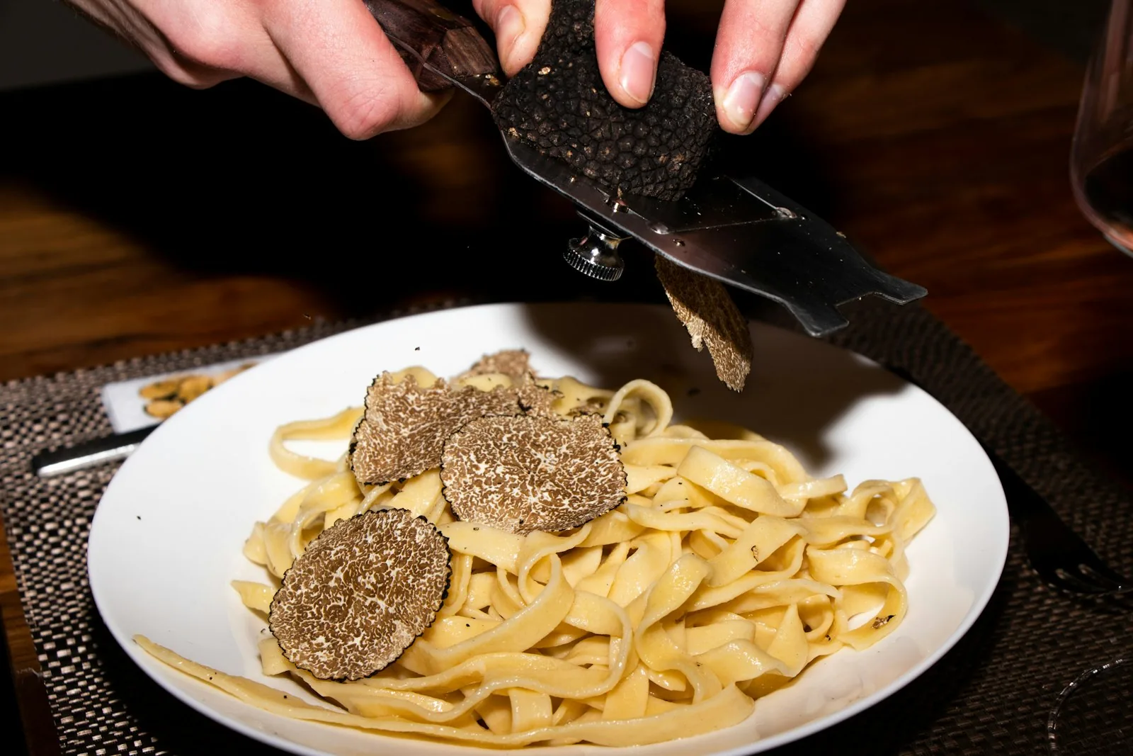 Shaving fresh black truffle over a plate of handmade pasta