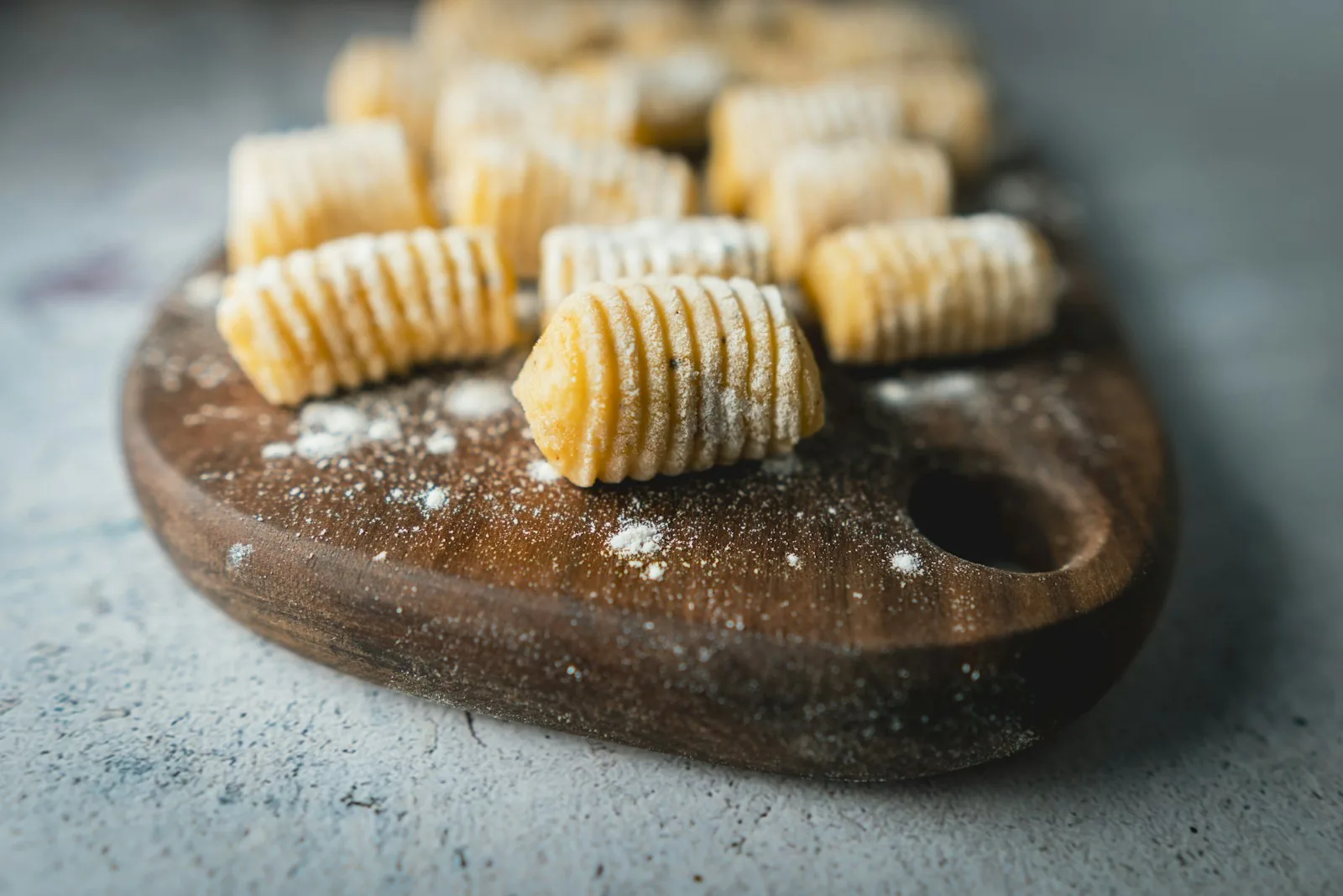 Fresh handmade njoki gnocchi dusted with flour on a wooden board