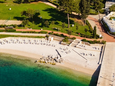 Lettini e ombrelloni disposti lungo la spiaggia di ghiaia di Santa Caterina