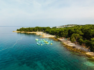 Het dennenbos op het schiereiland Borik gezien vanaf zee, met het waterpark bij het strand.