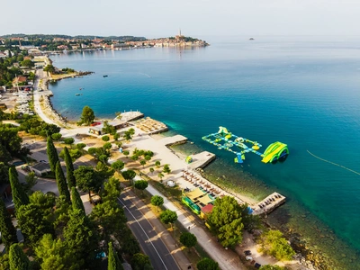 Plaža Porton Biondi z njenim plavajočim vodnim parkom, v ozadju stari del mesta Rovinj čez zaliv.