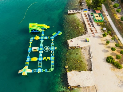 Plavajoči vodni park na morju – tobogani, plezalne konstrukcije in poligoni z ovirami.